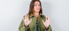 young lady in green jacket showing refusal gesture and looking reluctant , front view.